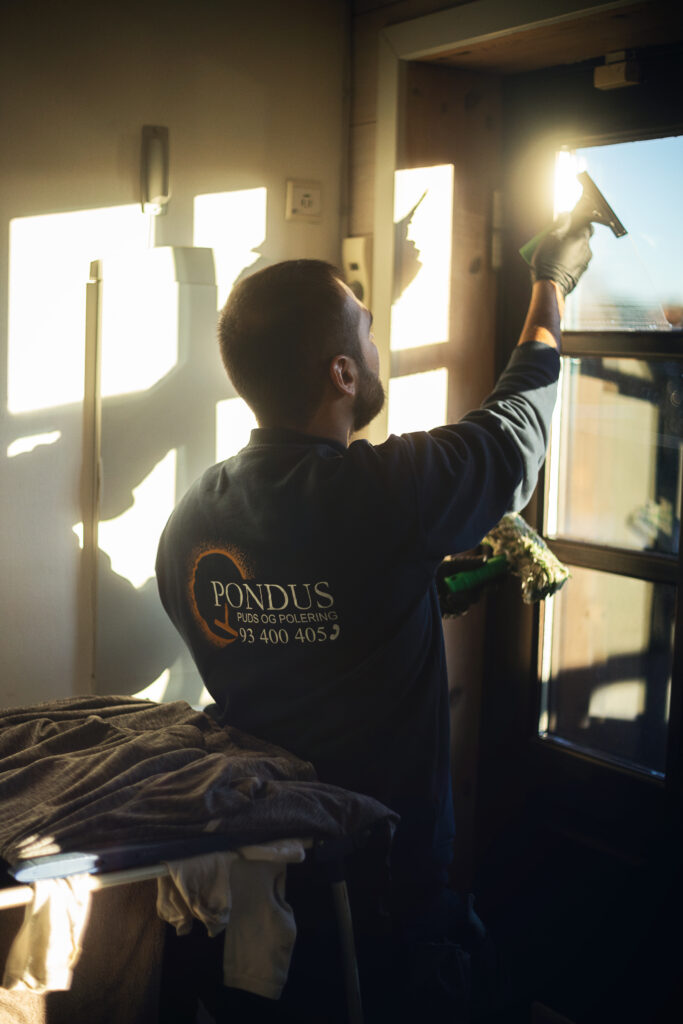 Mand pudser vinduer i sollys